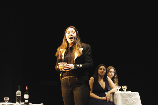 young woman singing on stage with a drink in her hand