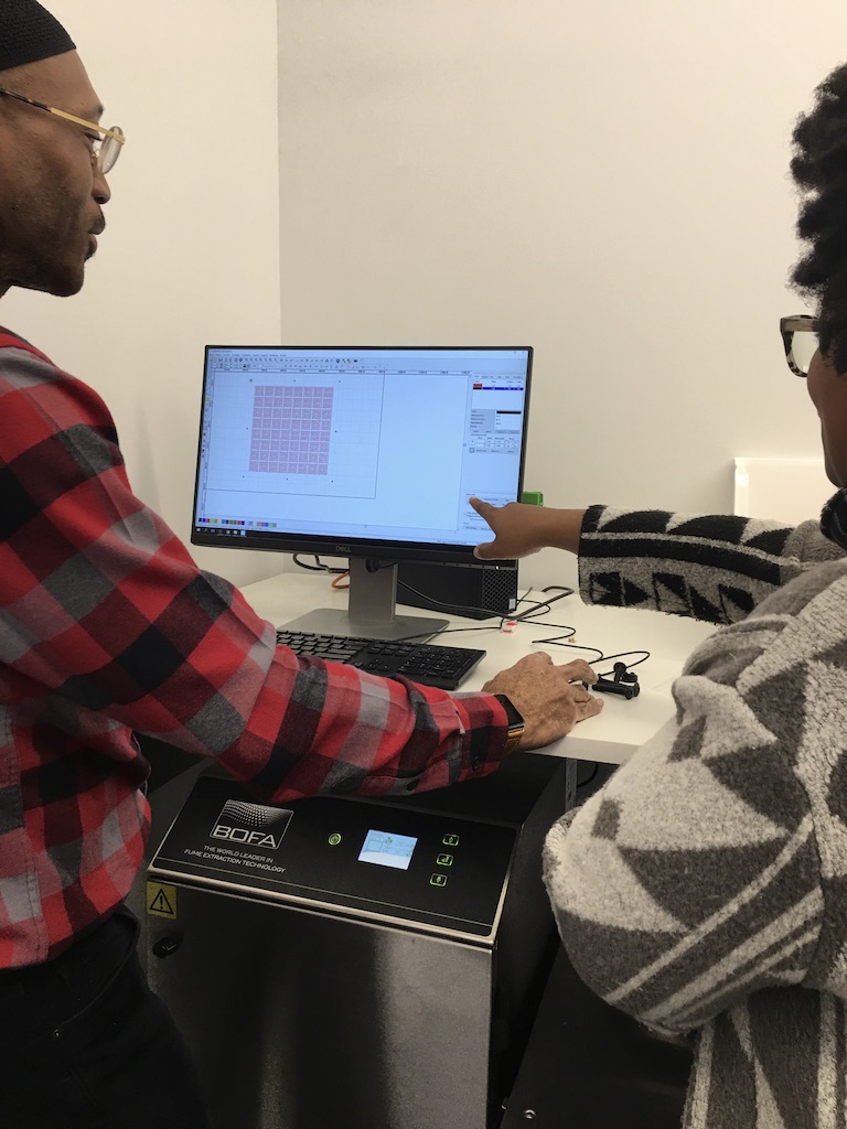 Aaron Kinard and Jen Brown of the Design Center operate software to control the laser cutter.