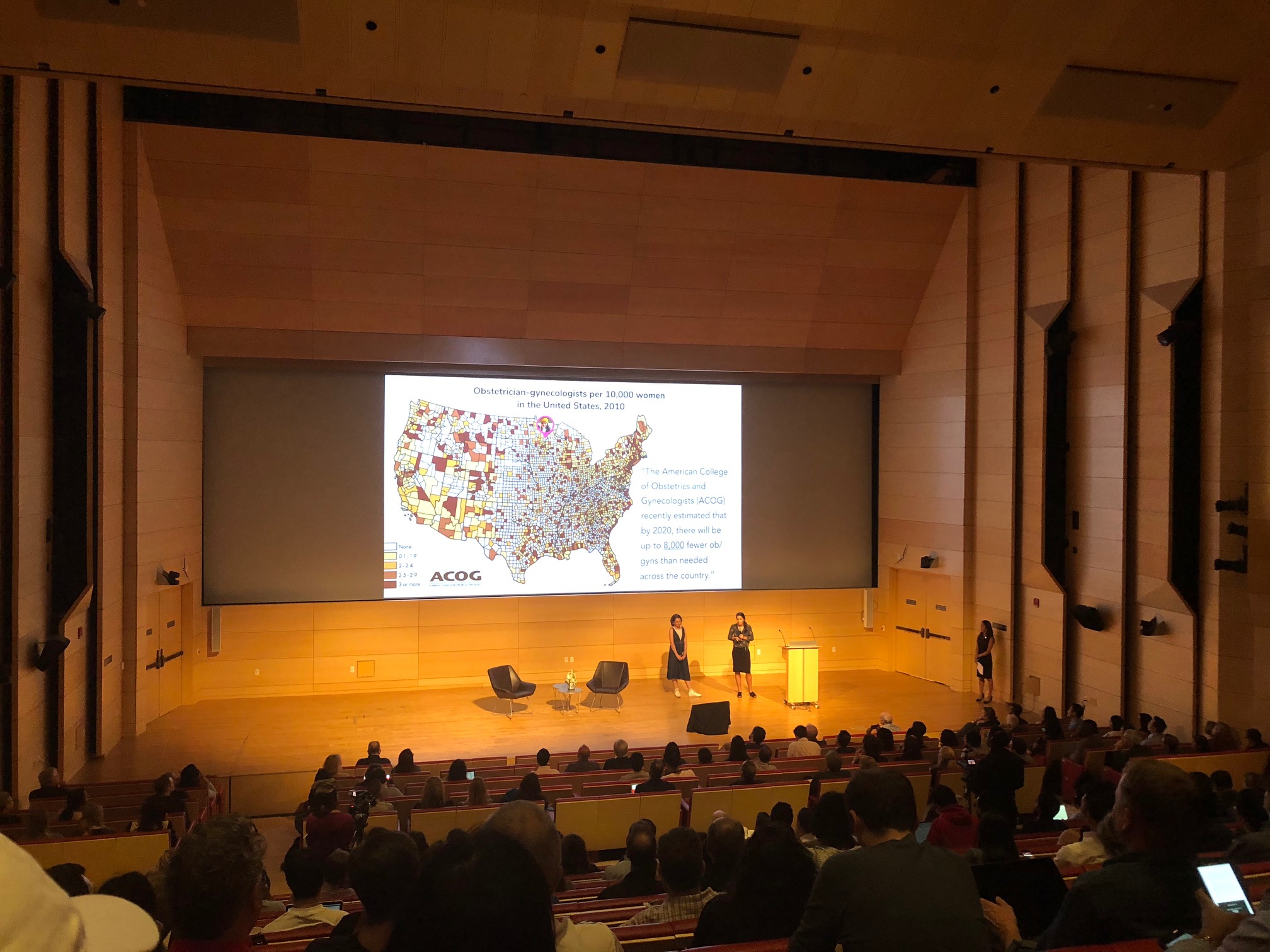 A slideshow with a map of the US being projected in an auditorium. 