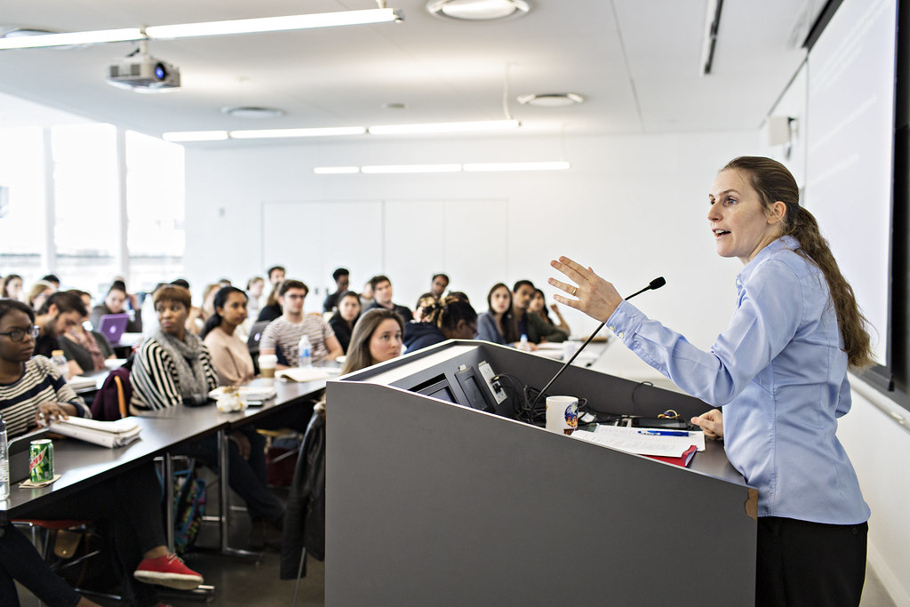 Image shows a live event with a speaker talking to the crowd