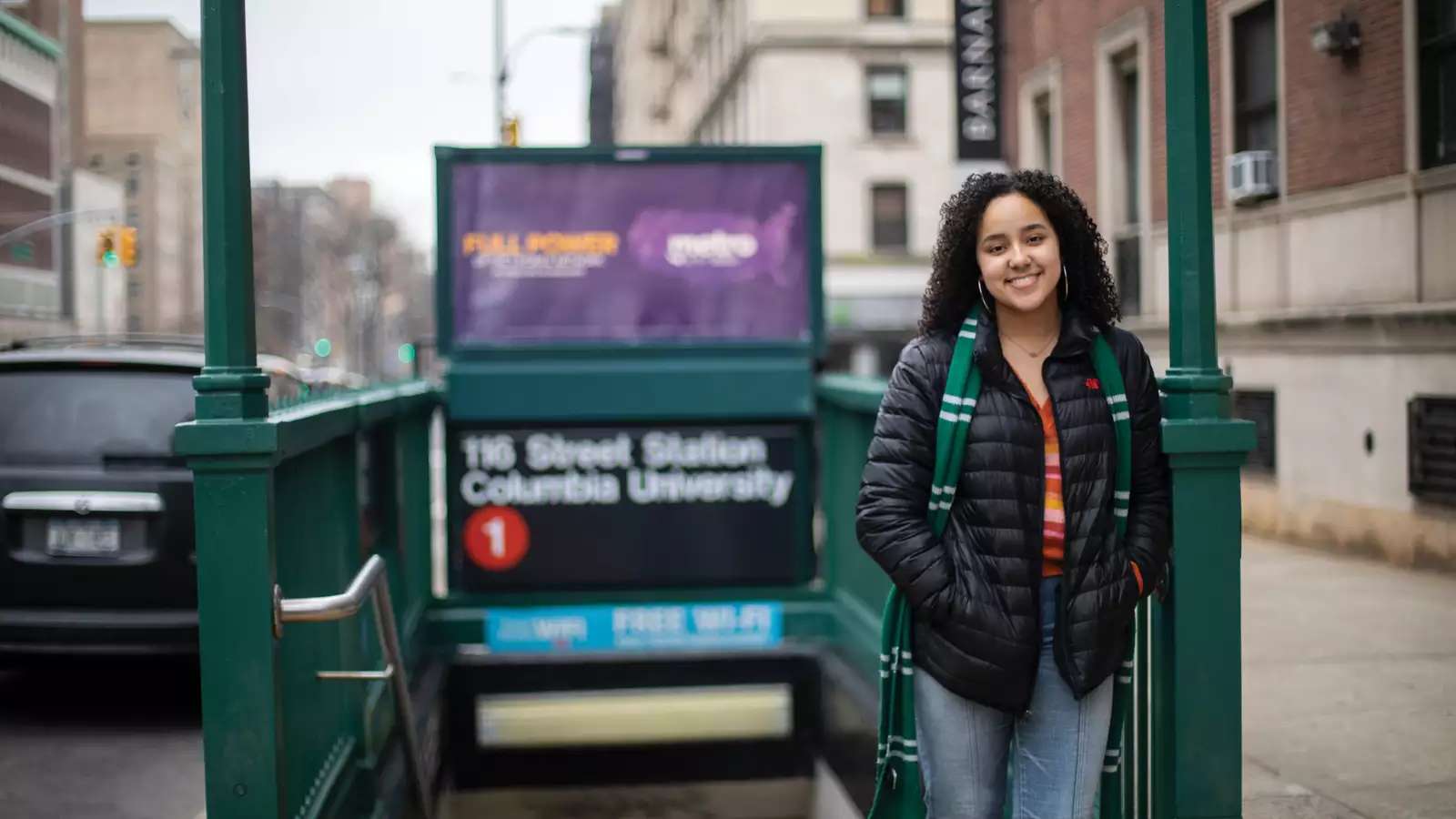 A young woman stands in front of the train entrance.