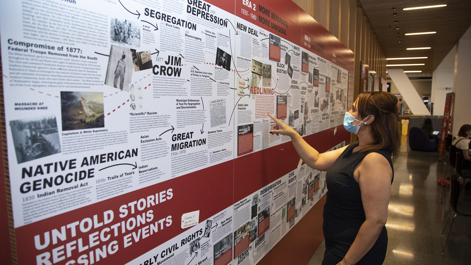 Woman pointing at exhibit text about redlining