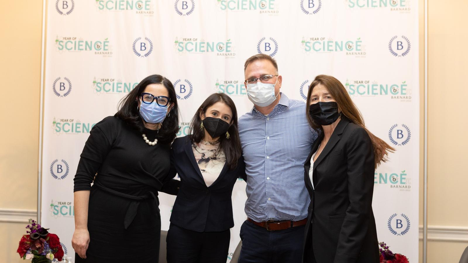 Four masked panelists stand in front of a backdrop with the Year of Science logo on it