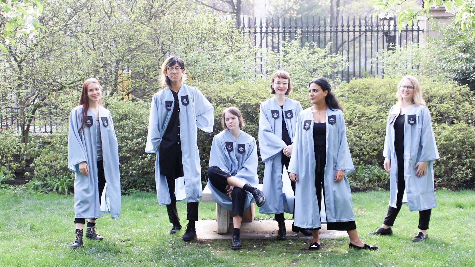6 young women in light blue graduation robes on Barnard's green campus