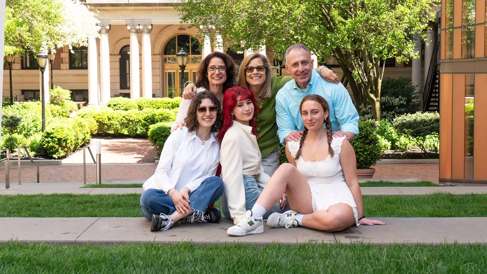 three staff parents stand behind their three seniors on campus