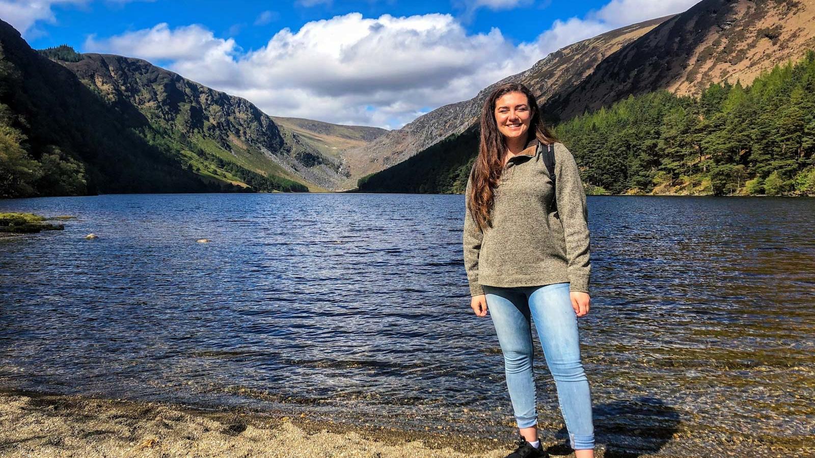 young woman stands next to a lake in Ireland
