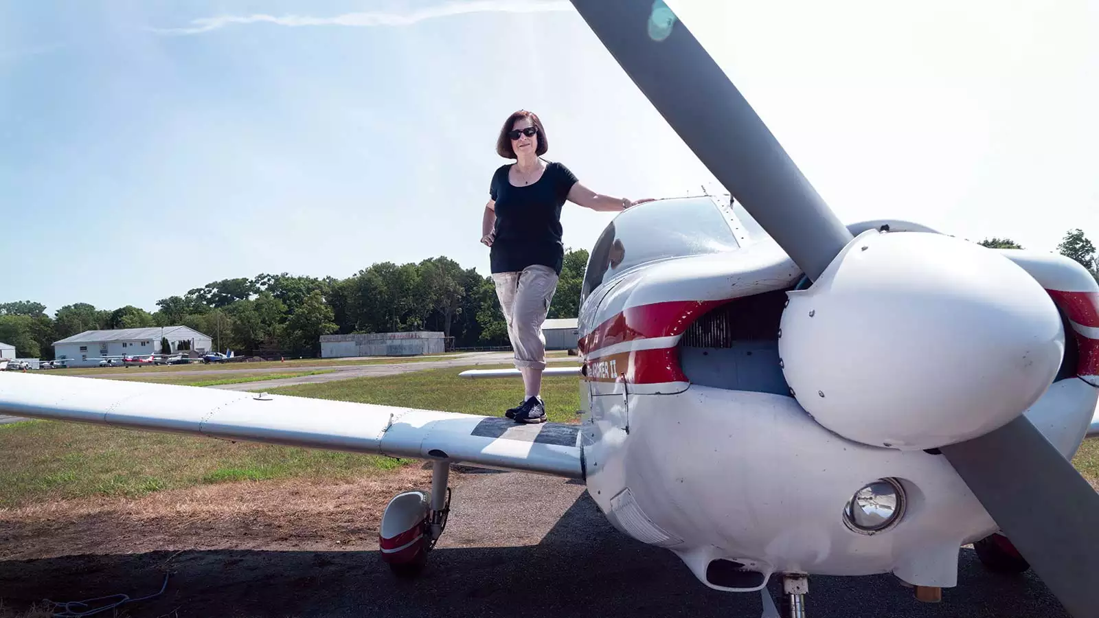 Beverly Weintraub stands on the wing of her small plane