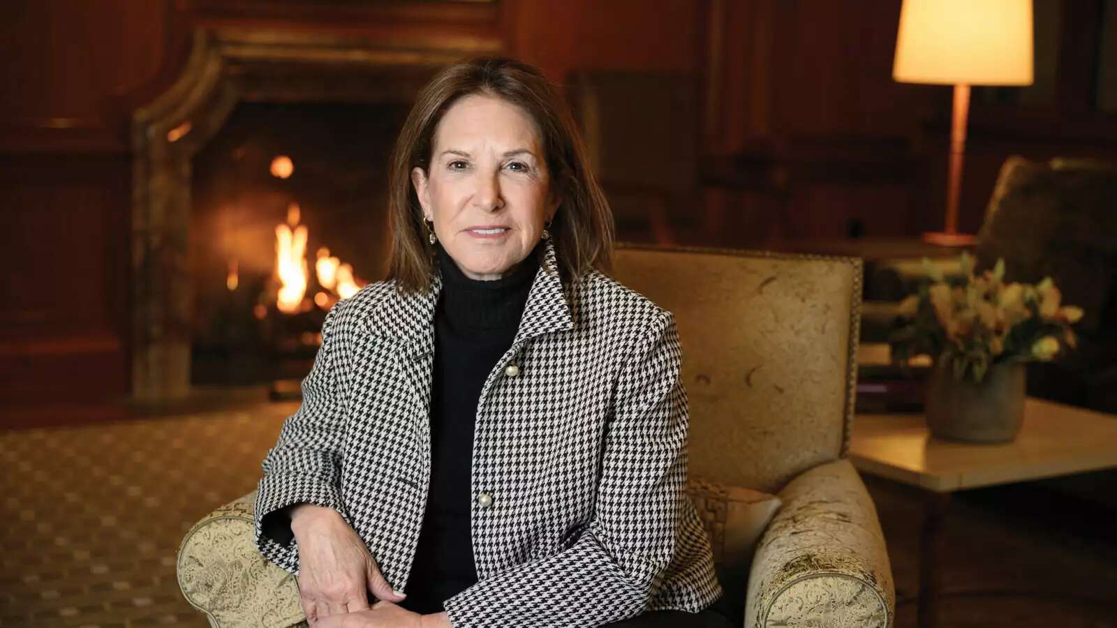 Woman wearing black and white sitting in chair in front of fireplace