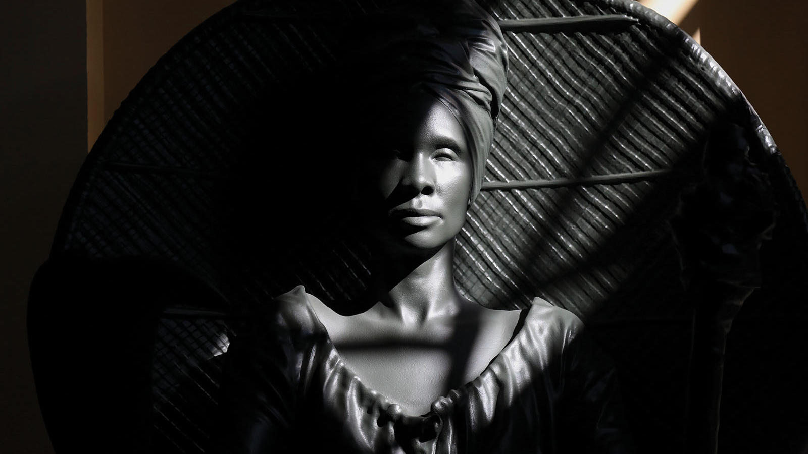 close up of the statue I Am Queen Mary, a Black woman seated in a rattan chair