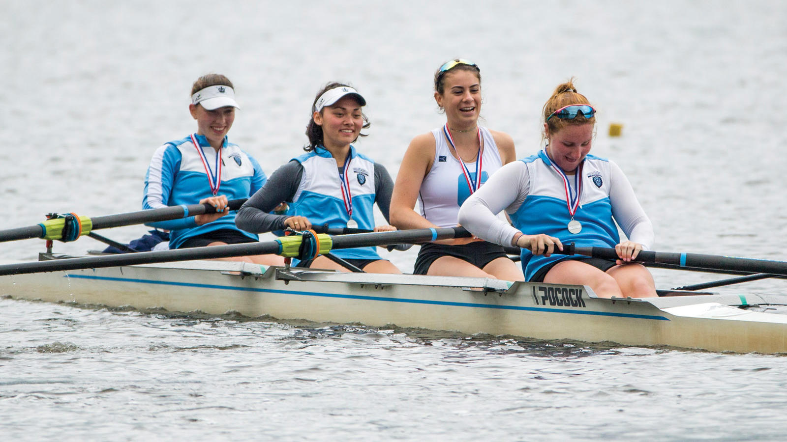 4 women rowing wearing Columbia blue and silver medals