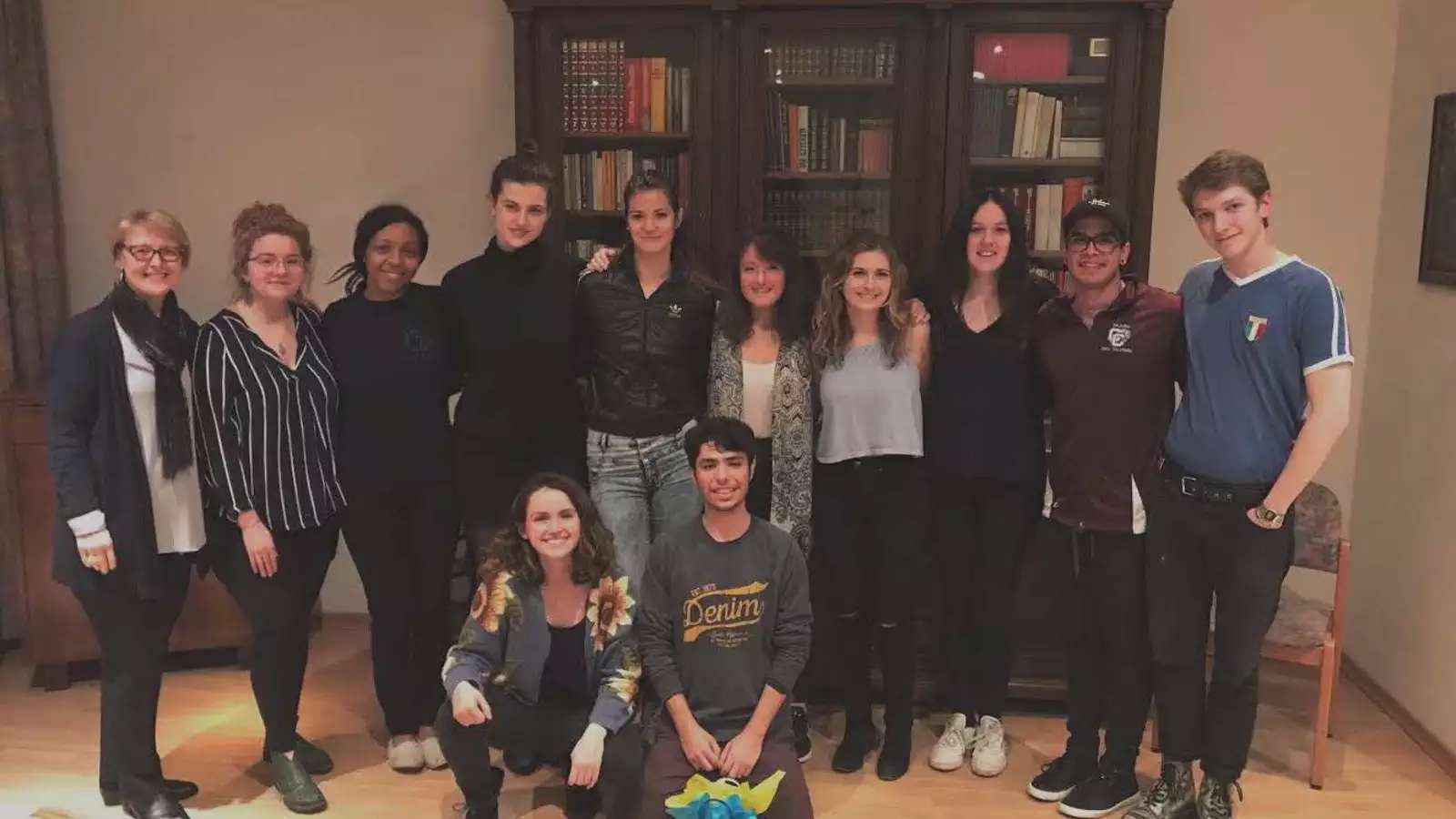 A group of students and a professor in front of a book case