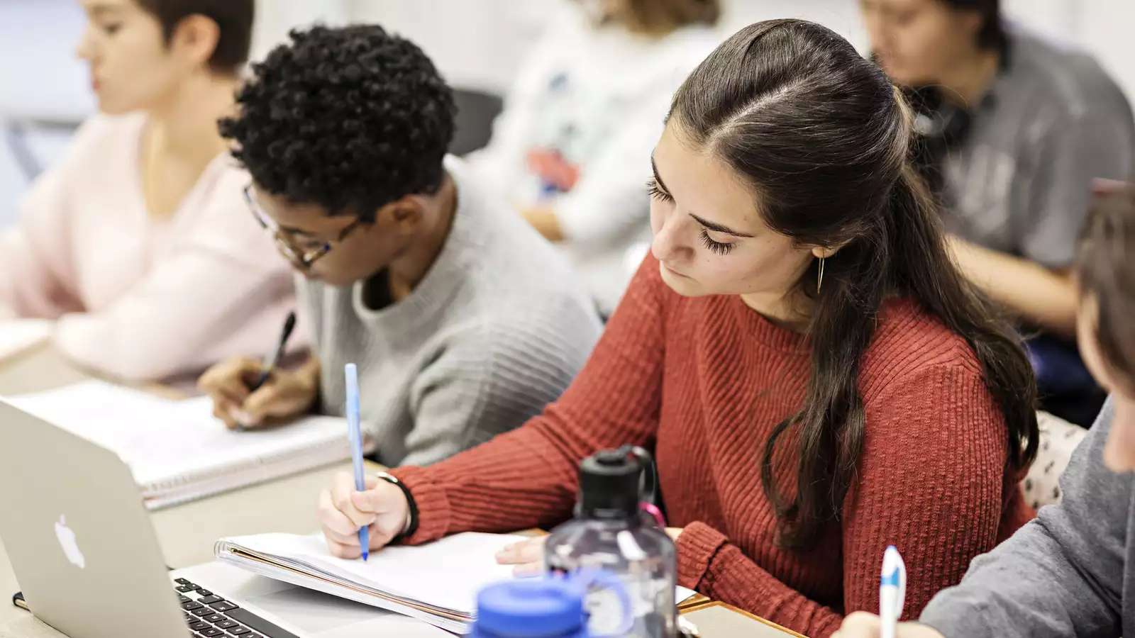 students in a classroom, writing in notebooks