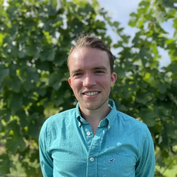 a white man standing outside looking directly into the camera and smiling.