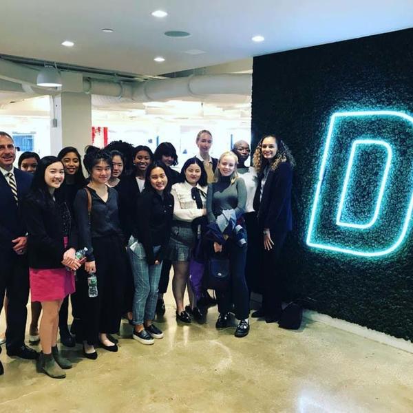Group of students next to a giant, neon "D"