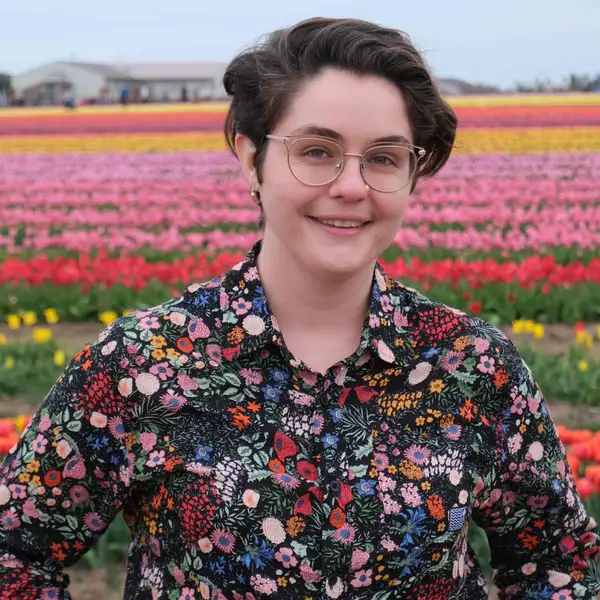 Meghan Hartman wearing a floral long sleeve shirt in a field of tulips