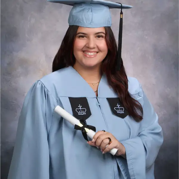 Young woman with dark hair wearing graduation cap and gown