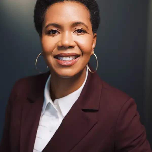 Photo of Professor Angela Simms wearing a white shirt under a brown blazer