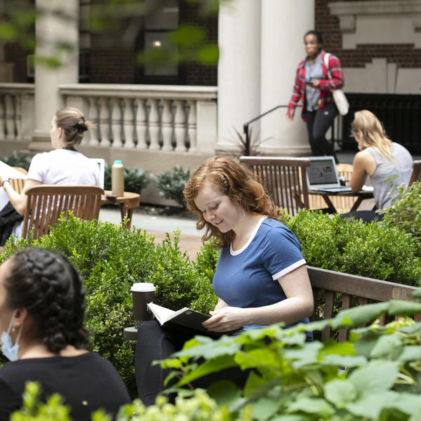 student reading on a bench in the quad 
