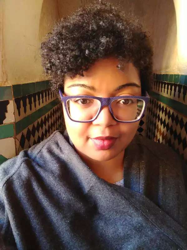 woman with short curly hair and glasses