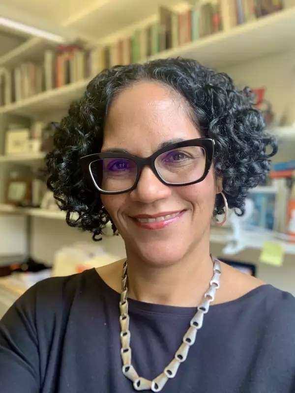 Monica L. Miller in front of bookshelves in her office.