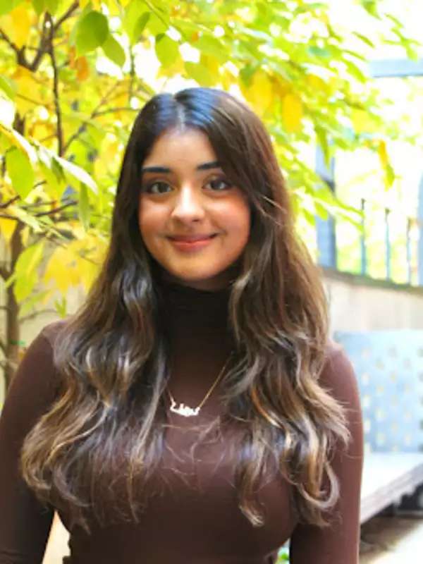 Noreen Mayat wearing a brown shirt in front of a tree.