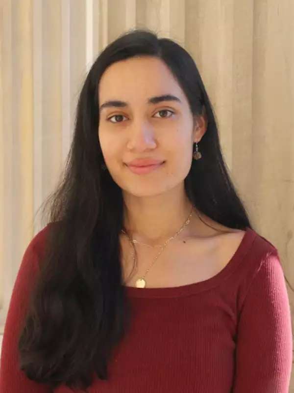 Shivani Tripathi wearing a red shirt in front of a pillar