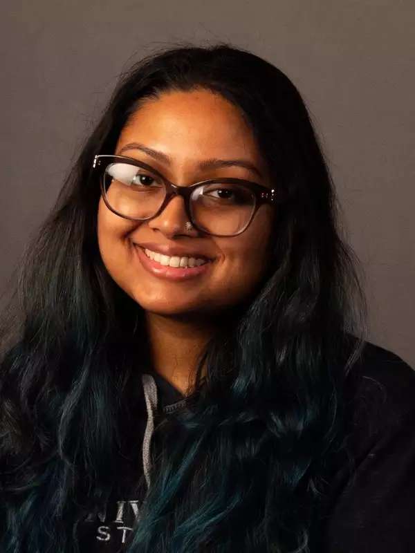 Brown woman sitting with long hair and glasses