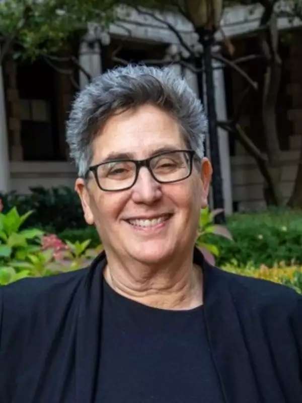 Photo of Prof. Debra Minkoff wearing a black top with the Milbank garden behind her