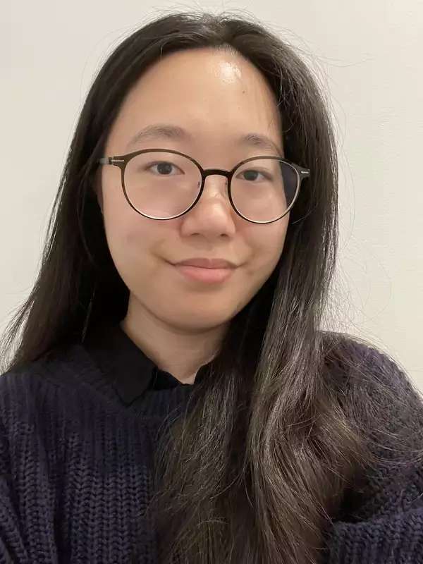 woman with long dark hair and glasses, wearing a dark sweater