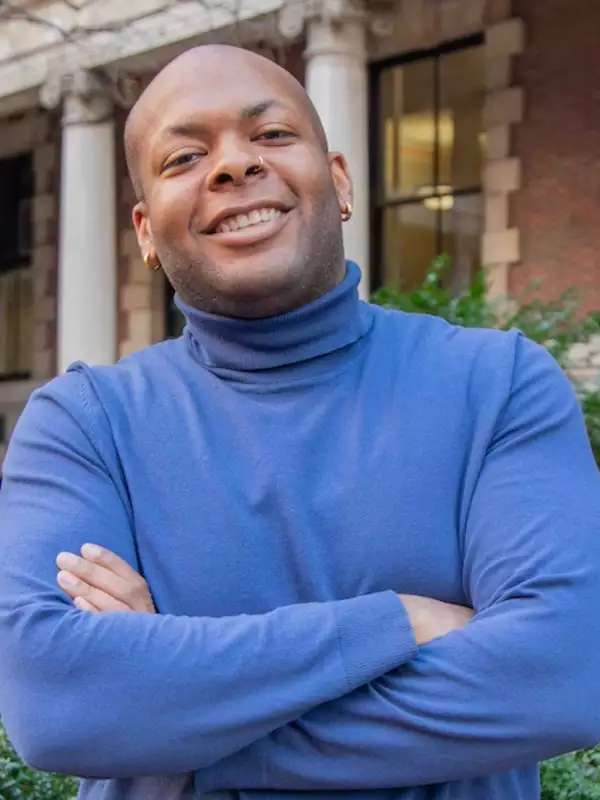 mixed background with man smiling with arms crossed, wearing a blue turtleneck 