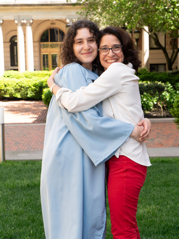 Two women hugging with the younger one in college regalia