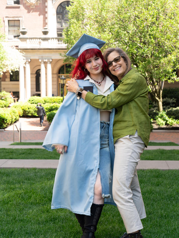 Two women hugging with the younger one in college regalia