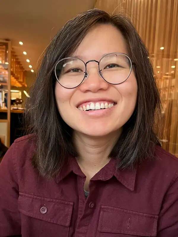 Woman with medium-length dark hair wearing glasses and a white shirt