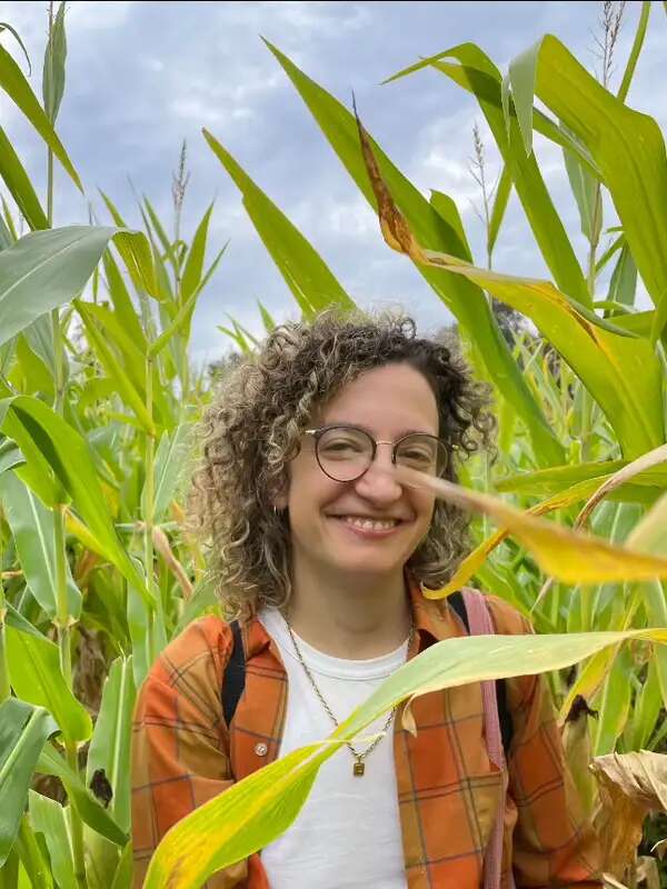 Daria Reaven in a corn field wearing an orange shirt. 