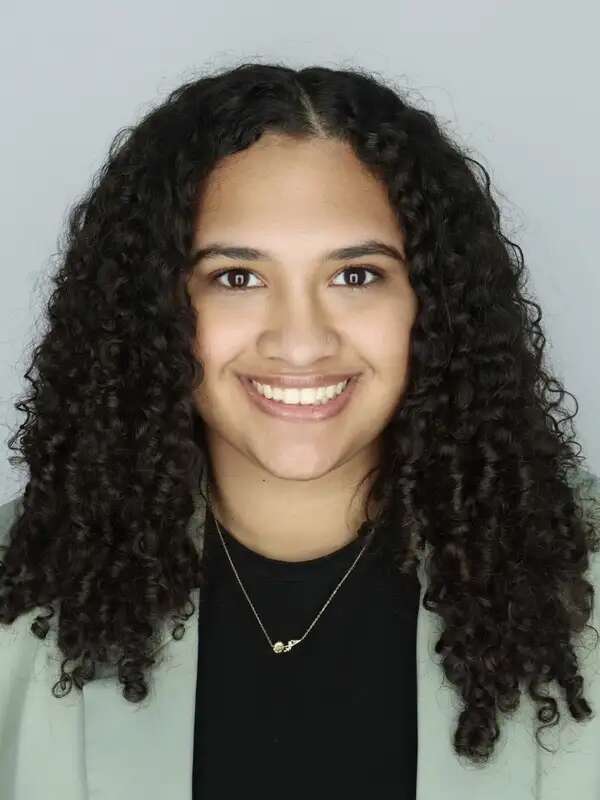 Headshot of woman with curly black hair smiling at camera