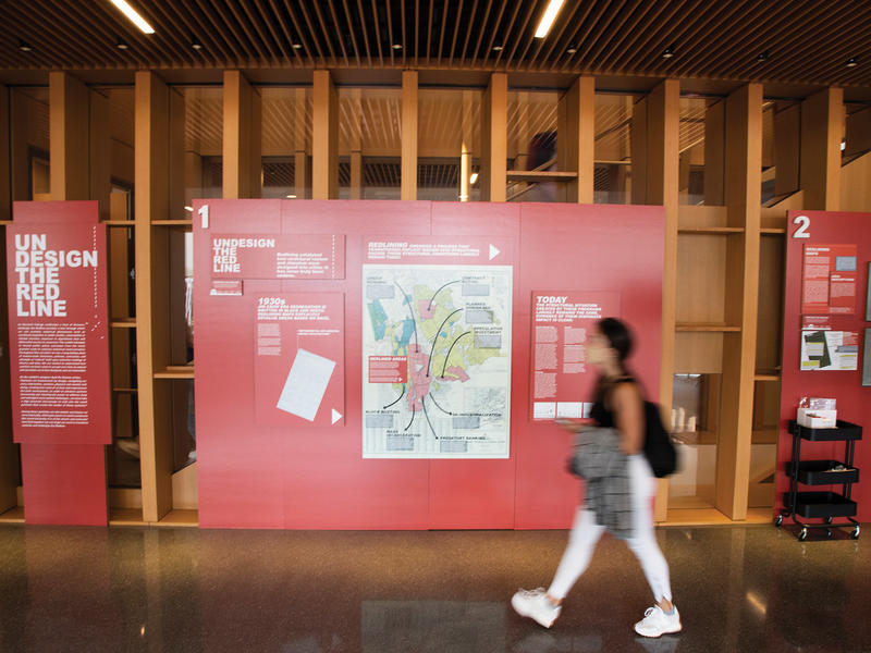 A student walks passed the "Undesign the Redline" display