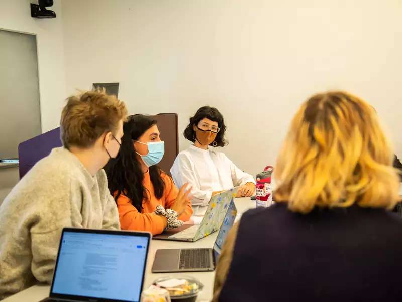 Camilla Sturm sits among students in a small classroom while she teaches