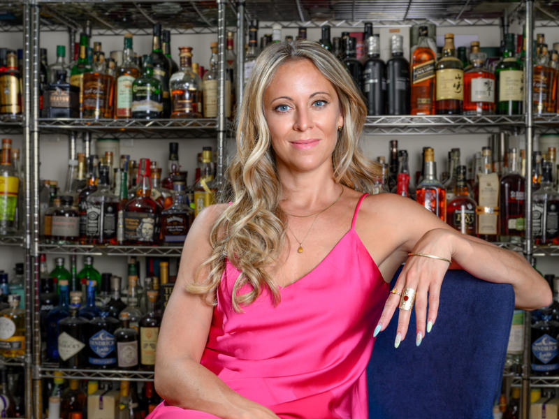 Pamela Wiznitzer sitting in front of alcohol bottles