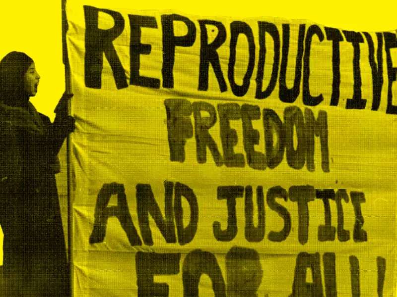 Muslim woman holds a sign, "Reproductive Freedom and Justice For All"