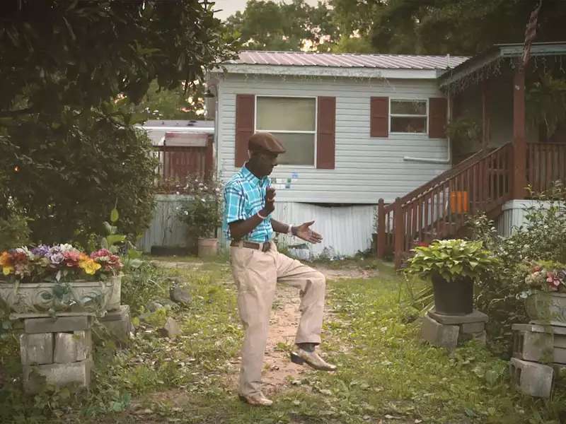 Black man in a grassy yard claps