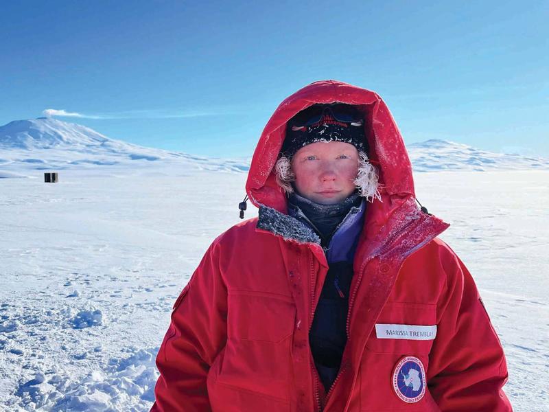 Marissa Tremblay in Antarctica. She is wearing a large red coat with the hood up.