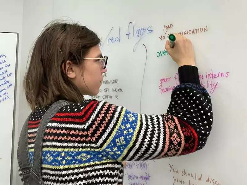 [Image description: A student writing on a whiteboard.]