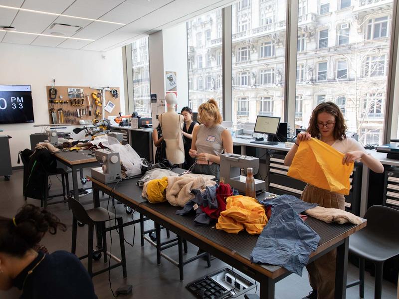 Students work with fabric in a large room with sewing machines