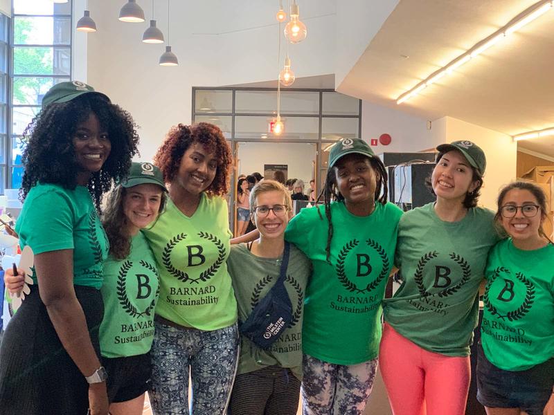 7 young women in green Barnard Sustainability shirts with their arms around each other