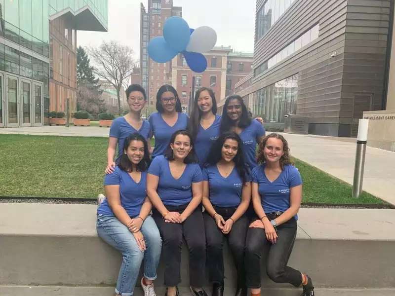 8 students posed outside, wearing matching blue shirts