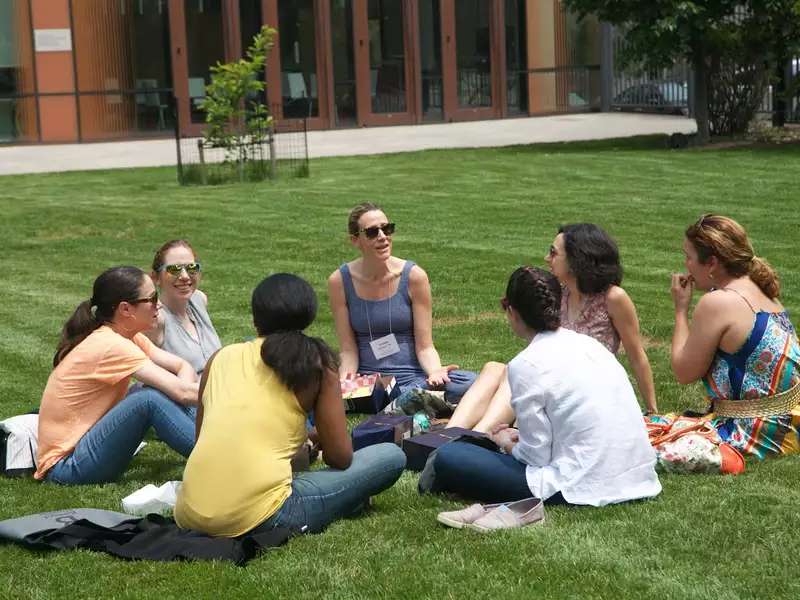 7 women seated in a circle on the grass
