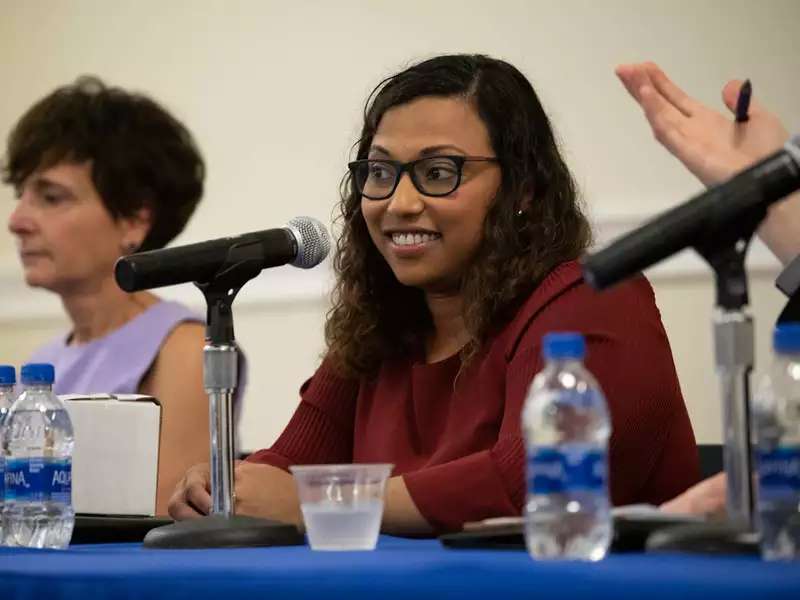 Woman of color seated on a panel with other women