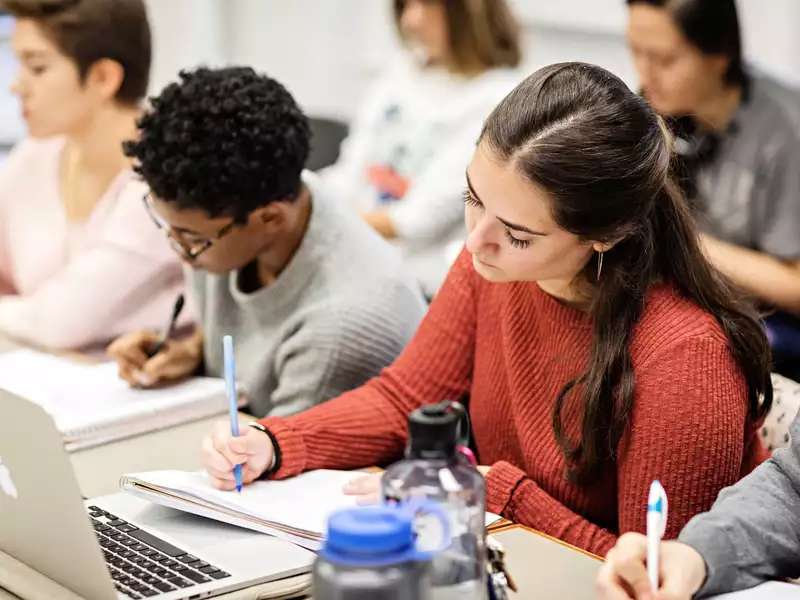 students in class taking notes by hand in notebooks