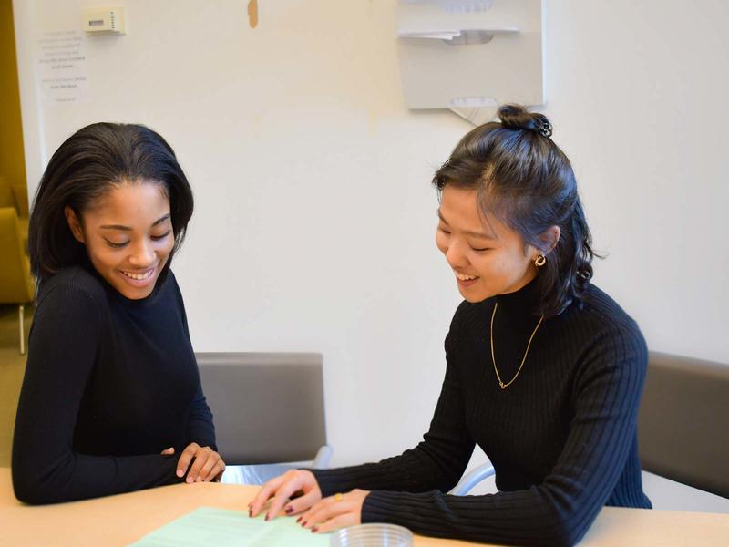 2 students of color working side by side on a writing project