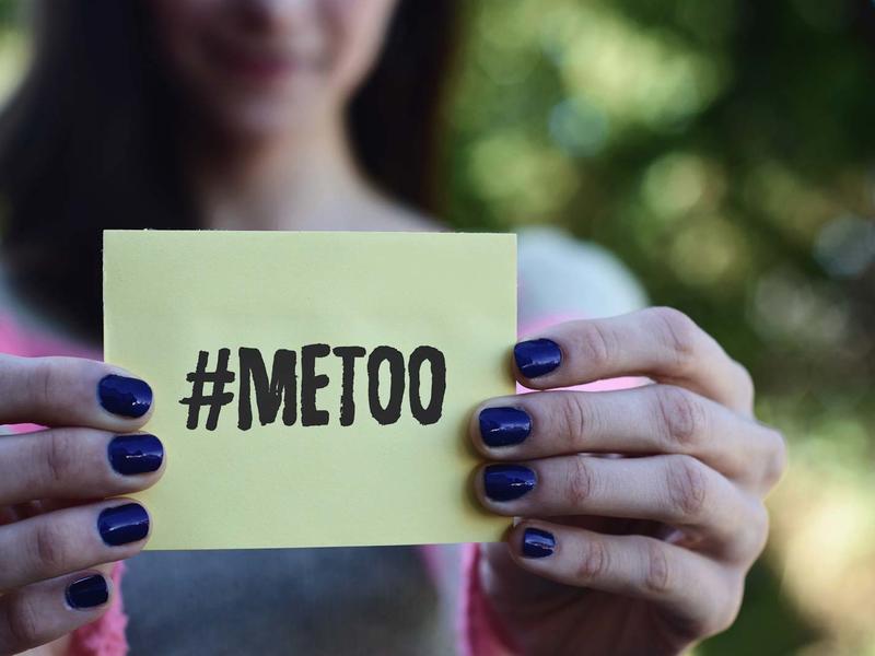 close up of a pair of hands holding up a note: #METOO